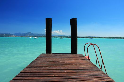  a small jetty in lake Garda Italy, fantastic colors in sky and water. Perfect for any sort of concept of vacations or tropics