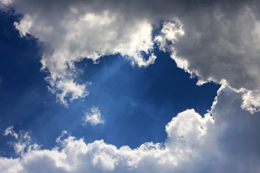 fantastic cloudscape on a blue sky, sun shining behind the clouds great for backgrounds or messages