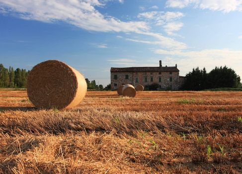 A close up of a hay bale on a corn field in Europe, shot in the warm afternoon sun farmhouse in the background, great warm feel to the image