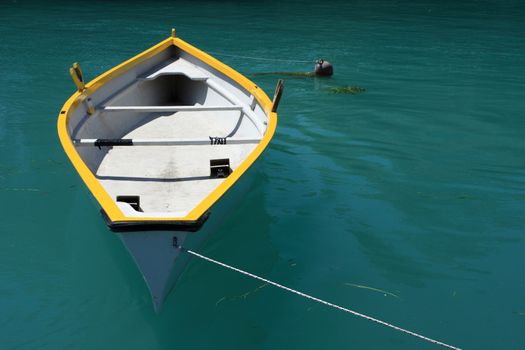 A yellow and white rowing boat on deep green water, plenty of copy space