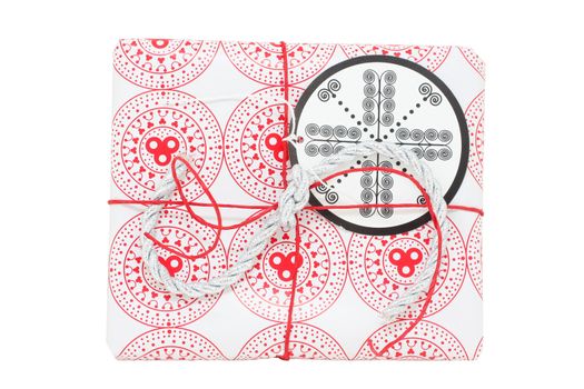 A gift wrapped in red and white paper, with gift tag, isolated on white