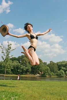 The sports beauty girl  in bikini jumps above a lawn