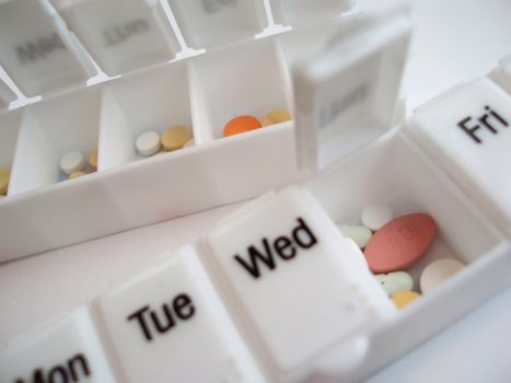 a weekly drug dispenser box with various pills inside        