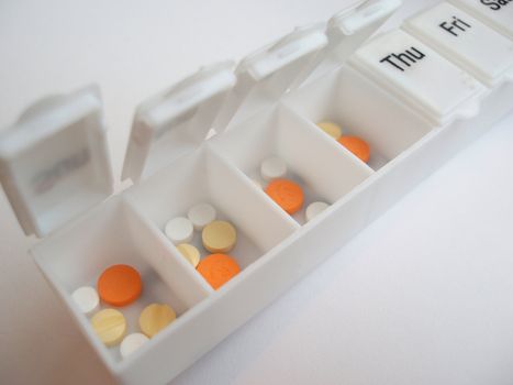 a weekly drug dispenser box with various pills inside        