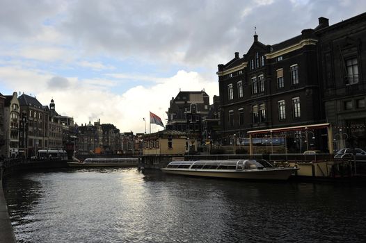 canal water reflecting Dutch buildings boats clouds and blue sky 