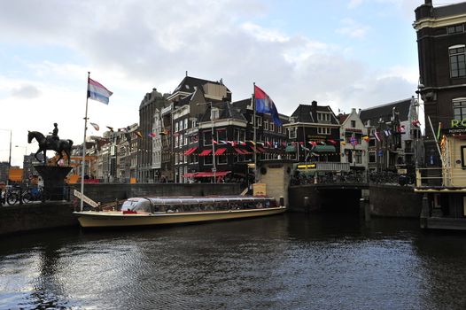 canal water reflecting Dutch buildings boats clouds and blue sky 