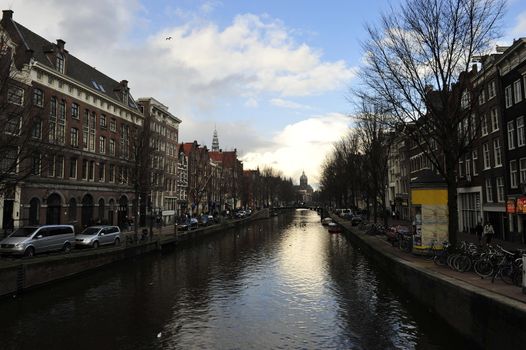 canal water reflecting Dutch buildings boats clouds and blue sky 