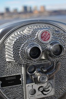 A closeup of a silver tourist viewer with city background.