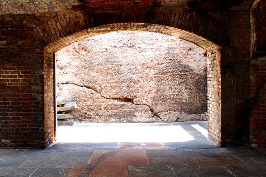 A brick arch way with daylight shinny through.