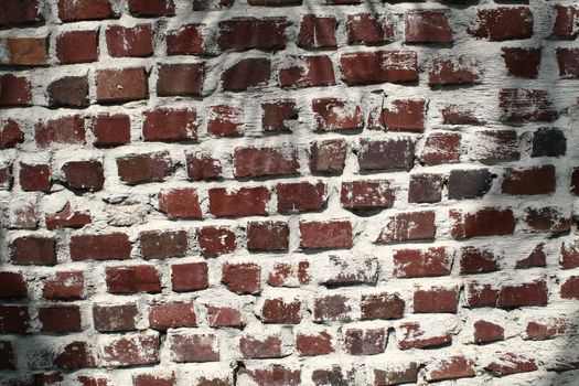 A wall of very weathered and aged bricks.