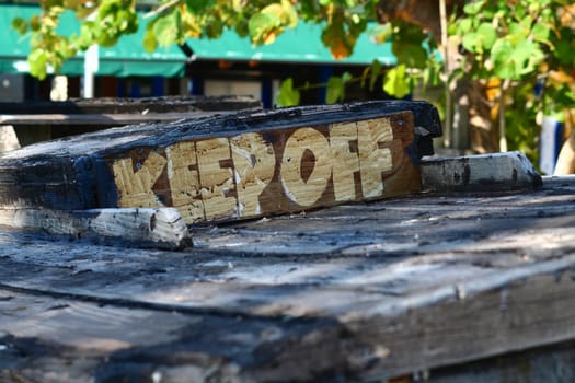 A very rustic Keep Off sign on the deck of a boat.