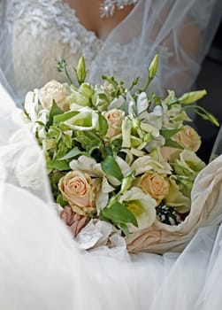 Wedding bouquet from roses and chrysanthemums on a background of a dress