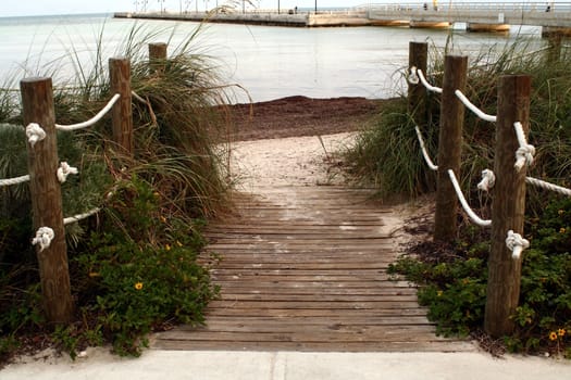 A boardwalk to the beach flanked by nautical line.