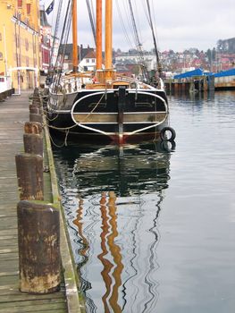 Traditional wooden tall sailboat reflected in the water in Svendborg Marina Denmark