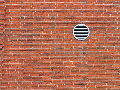 Red bricks wall with a small ventilation window - architecture abstract