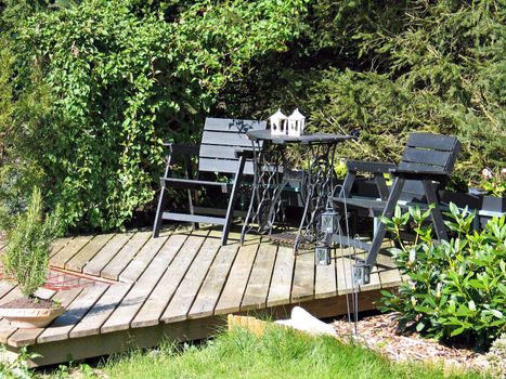 Beautiful wooden deck with furniture in a green garden
