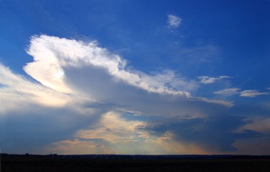 raining clouds in blue sky on horizon