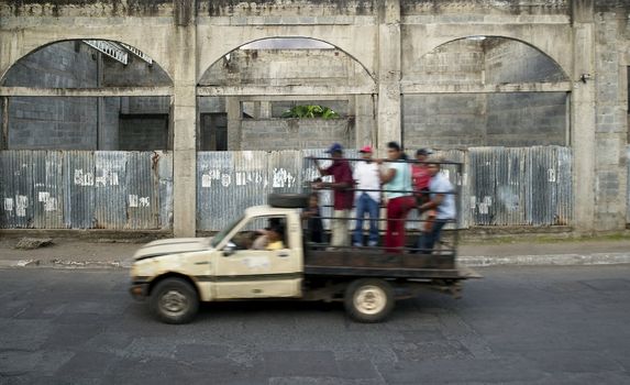 Truck full of people drives by abandoned building in Granada Nicaragua