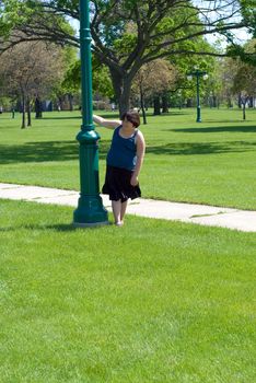 A young girl spinning around a light pole outside with additional space for text