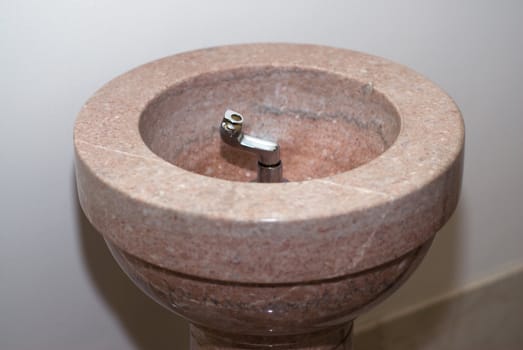 A marble drinking fountain with faucet shot indoors