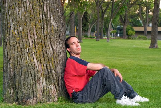 A young man sitting in a park, taking a break from work