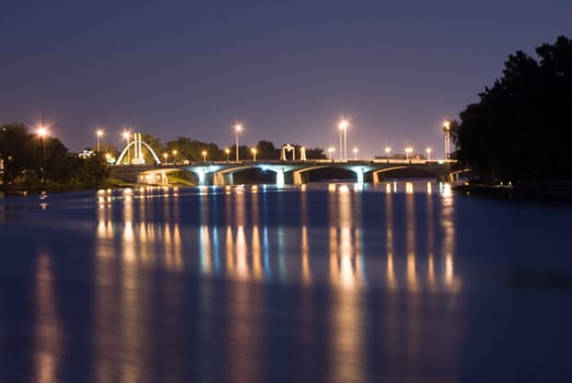 A view of a city bridge with reflections on the river