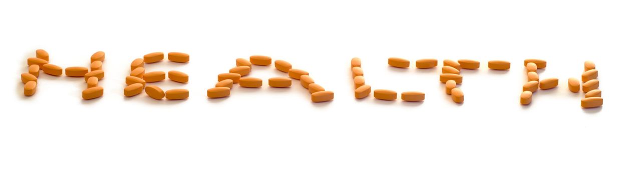 A group of pills spelling the word health, isolated on a white background