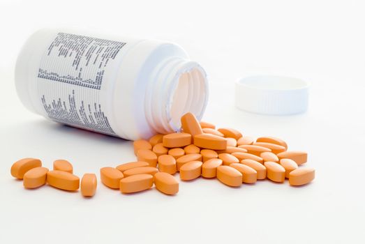 Healthy vitamins pouring out of a container, isolated on a white background