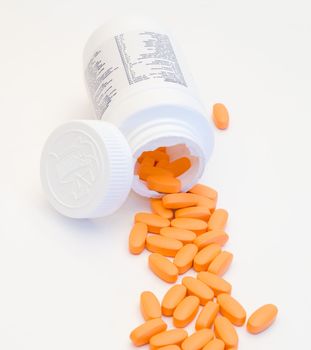 A bunch of pills pouring out of a pill container, isolated on a white background