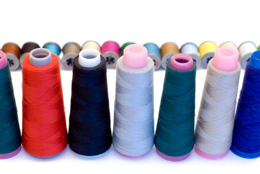 Spools of sewing thread lined up in rows, isolated on a white background