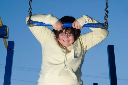 A young girl playing on playground equipment during the evening