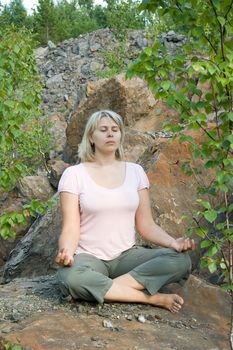 The meditating woman in a lotus pose on the nature