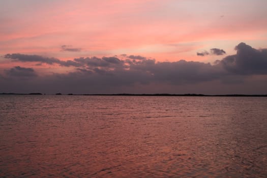 The sky and water turning pink during a sunset.