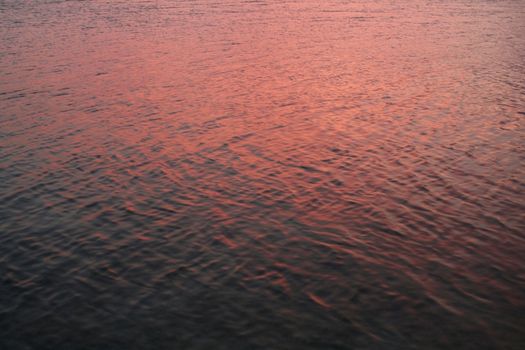 The ocean water reflecting the pink sky during sunset.