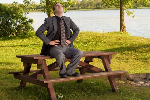 A young businessman wearing a grey suit doing deep breathing exercises