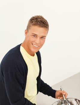 Handsome smiling young blond man busy with cooking