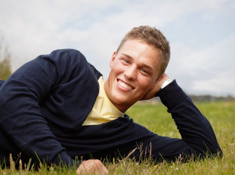 Happy young blond man lying on the grass