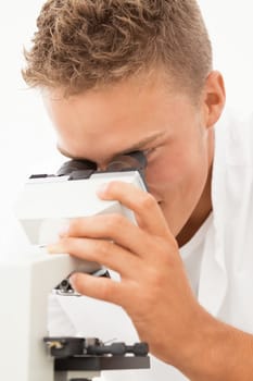 Young smiling researcher inspects something in microsope