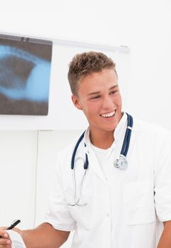 Smiling young doctor with phonendoscope having good news about patient diagnosis;