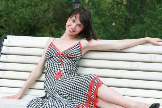 The beautiful girl poses on a bench