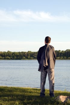 A businessman relaxing by a small lake after work