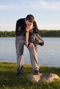 A young worker wearing a business suit holding his head with a headache