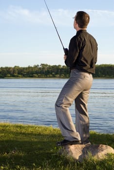 A young businessman at the lake fishing after work