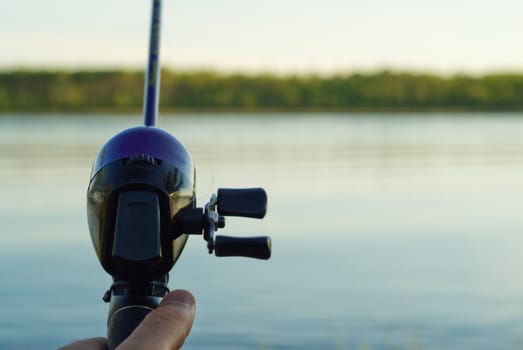 Closeup of a fishing reel casting over a lake
