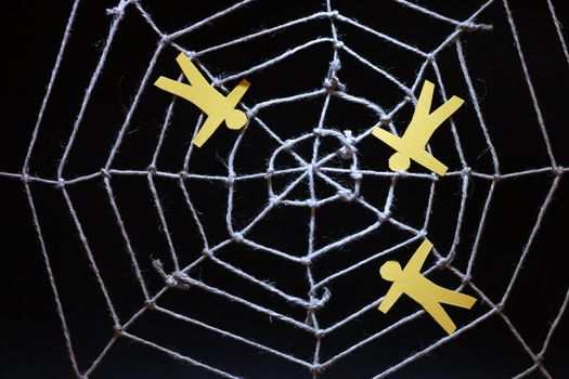 Conceptual background with web made from rope and yellow paper men on dark