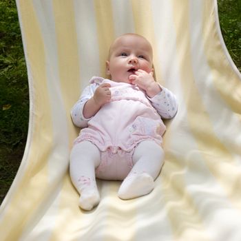 Baby girl
relaxing in striped hammock on a summer day