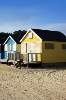 Blue and yellow wooden beach huts located on the coast at Chrstchurch, Dorset Hampshire UK.