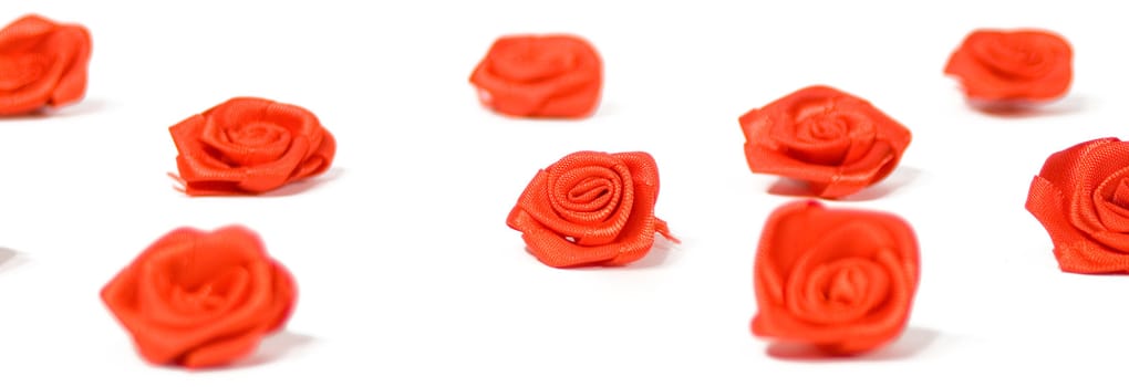 Fake red roses scattered on a white background