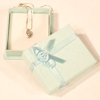 A diamond necklace laying in a small gift box