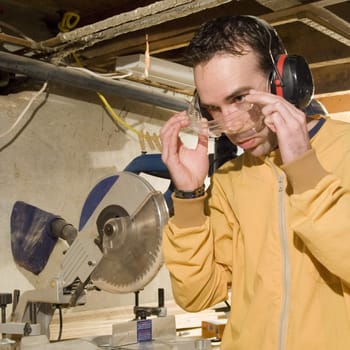 Young male putting on his safety goggles before using his power tools